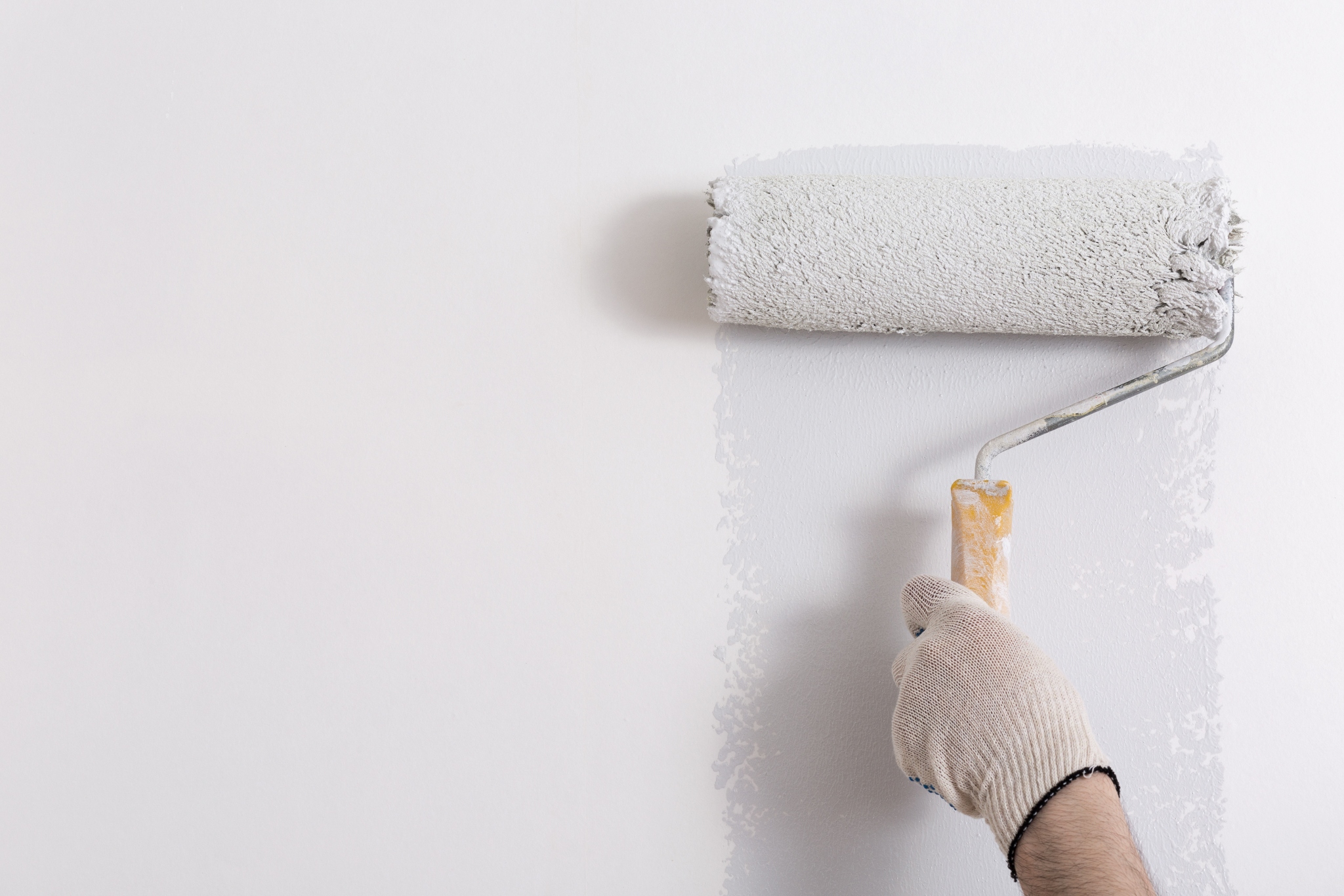 Some usign a paint roller to apply low VOC paint to a hotel bathroom.