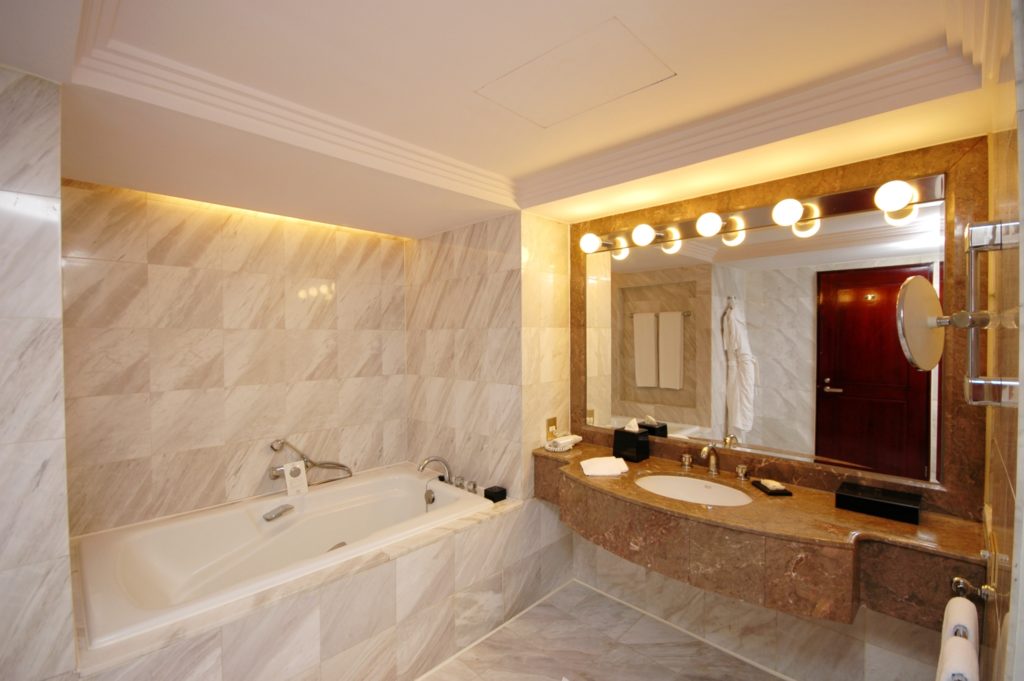 A spacious hotel bathroom with a refinished hotel bathtub.